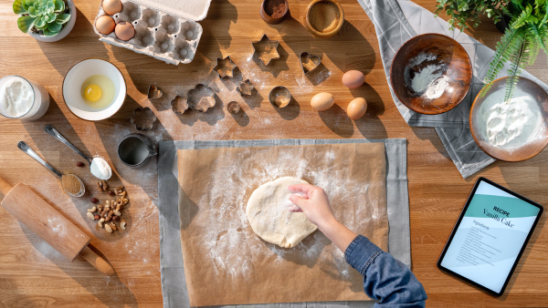 A top view of unrecognizable woman baking biscuits, desktop concept.