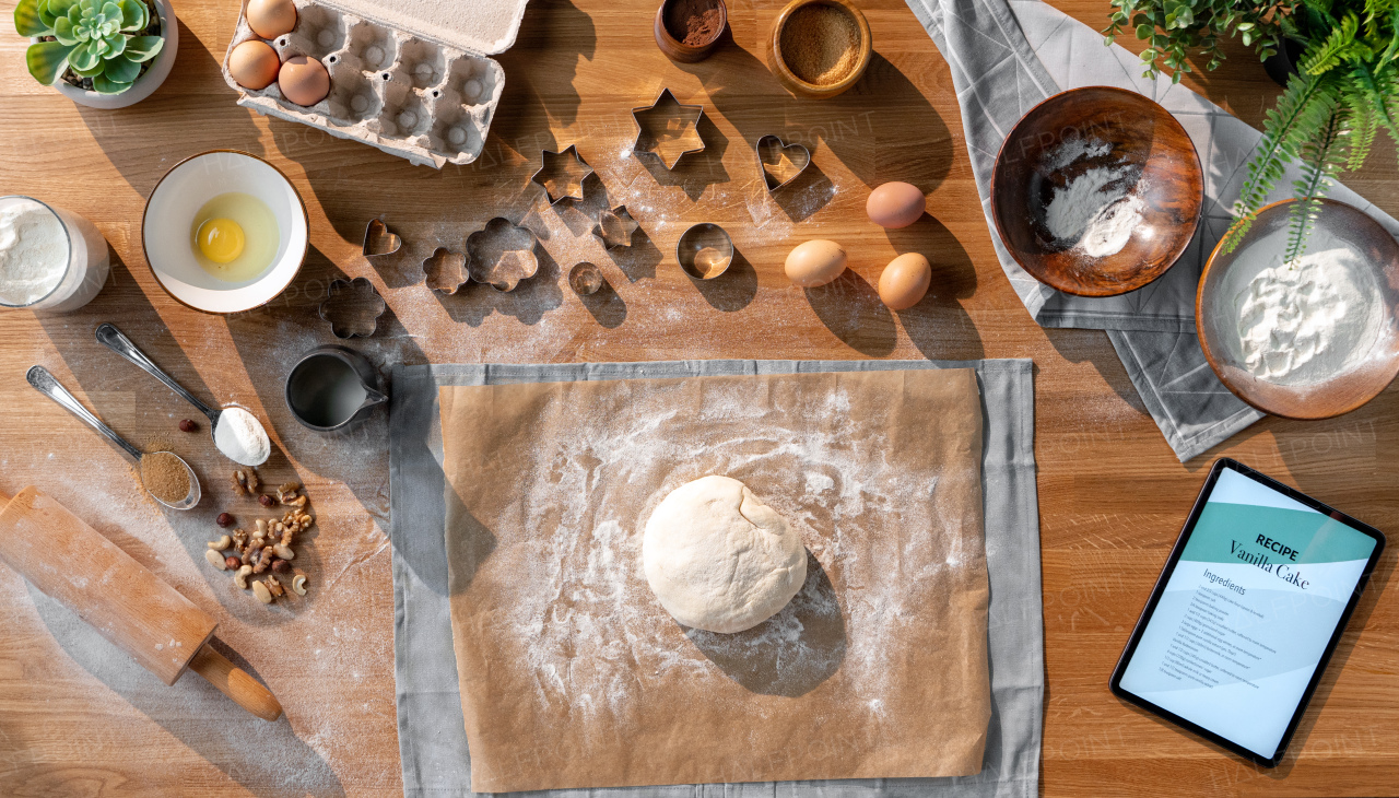 A flat lay top view of dough and baking ingredients, desktop concept.