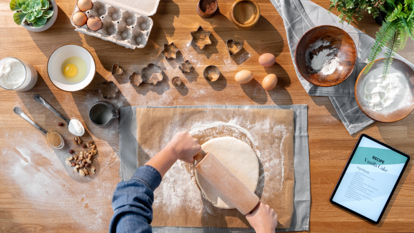 A top view of unrecognizable woman baking biscuits, desktop concept.