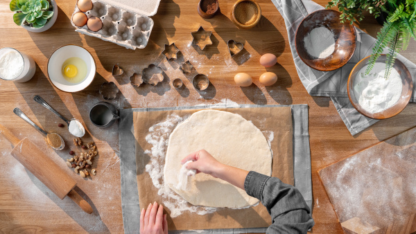 A top view of unrecognizable woman baking biscuits, desktop concept.