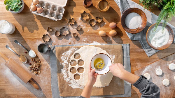 A top view of unrecognizable woman baking biscuits, desktop concept.