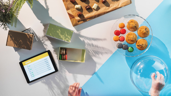 A top view of unrecognizable woman packing biscuits, processing orders desktop concept.