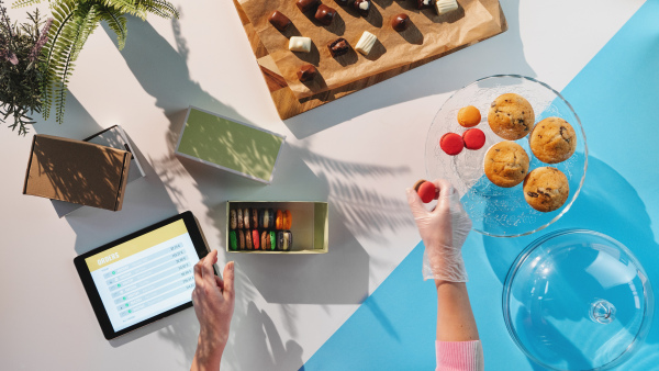 A top view of unrecognizable woman packing biscuits, processing orders desktop concept.