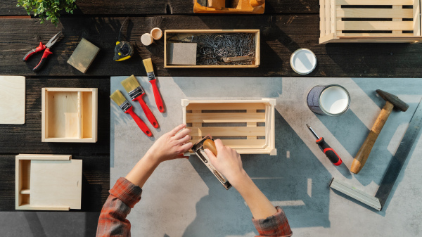 A top view of unrecognizable woman making wooden boxes, small business and desktop concept.