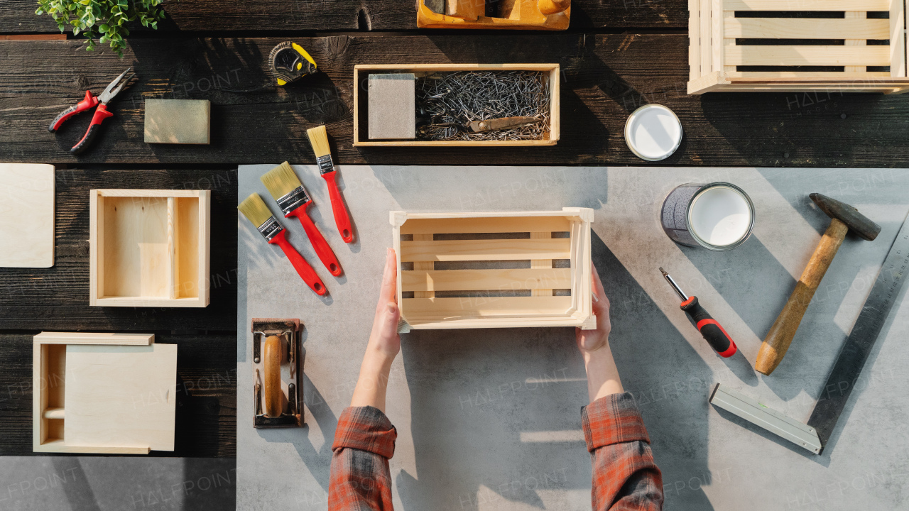 A top view of unrecognizable woman making wooden boxes, small business and desktop concept.