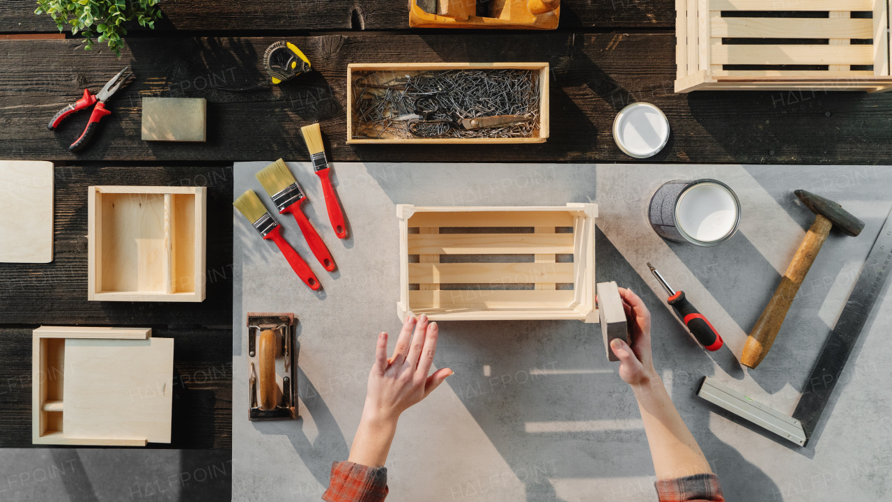 A top view of unrecognizable woman making wooden boxes, small business and desktop concept.