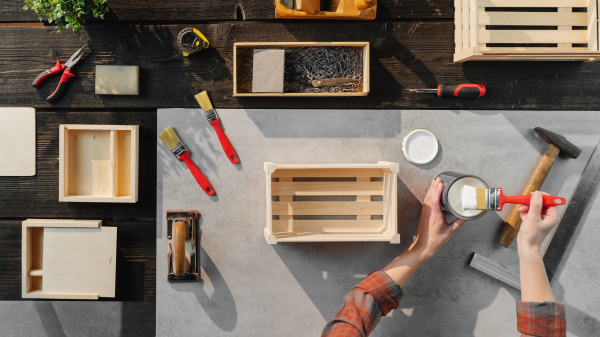 A top view of unrecognizable woman making wooden boxes, small business and desktop concept.