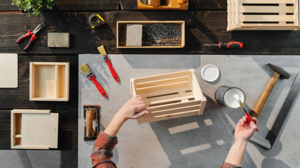 Top view of unrecognizable woman making and painting wooden boxes, small business and desktop concept.