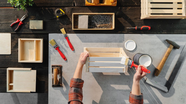 A top view of unrecognizable woman making wooden boxes, small business and desktop concept.