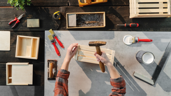 A top view of unrecognizable woman making wooden boxes, small business and desktop concept.