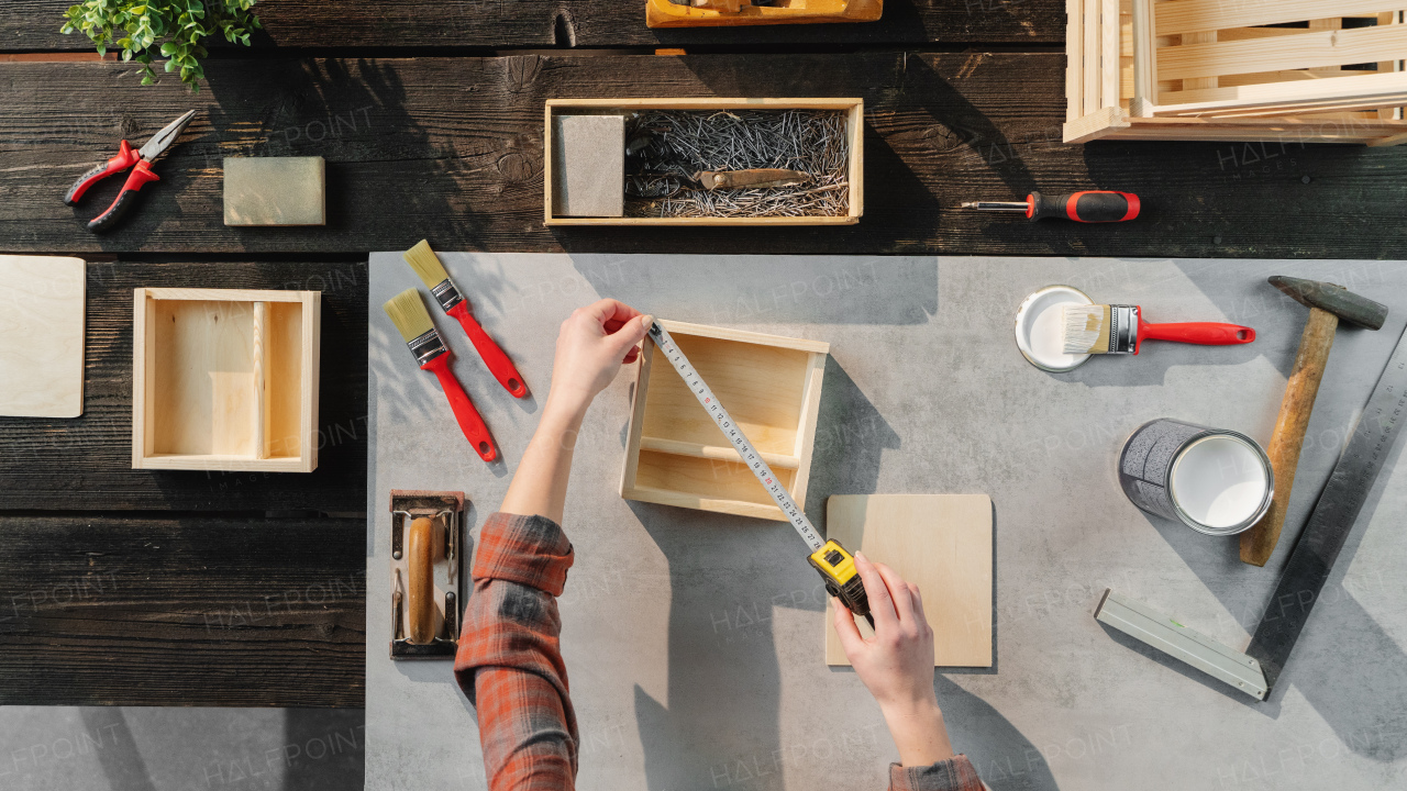 A top view of unrecognizable woman making wooden boxes, small business and desktop concept.