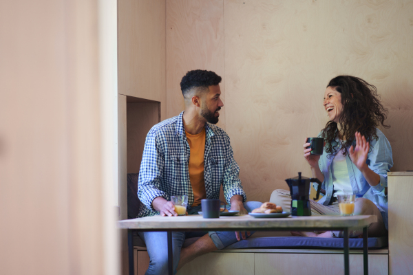 A happy couple in love sitting, resting and talking indoors in a tree house, weekend away and digital detox concept.