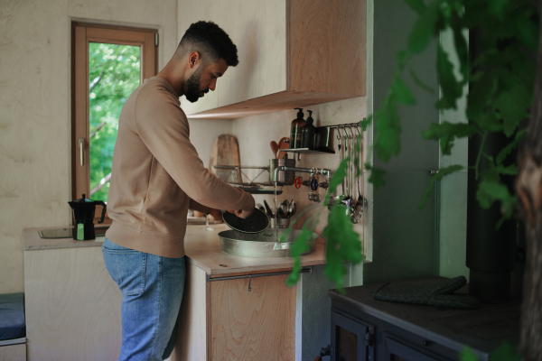 A happy young man washing up indoors in a tree house.