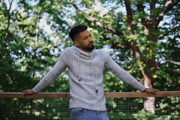 A front view of happy young man resting outdoors in forest, weekend away and digital detox concept.