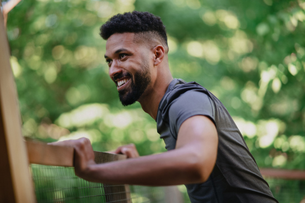 A happy young man doing exercise outdoors on terrace of tree house, weekend away and digital detox concept.