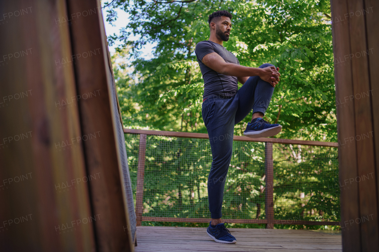 A young man doing exercise outdoors on terrace of tree house, weekend away and digital detox concept.