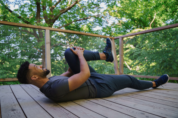 A happy young man doing exercise outdoors on terrace of tree house, weekend away and digital detox concept.