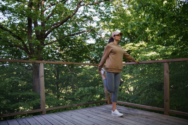 A mid adult woman doing exercise outdoors on terrace of tree house, weekend away and digital detox.