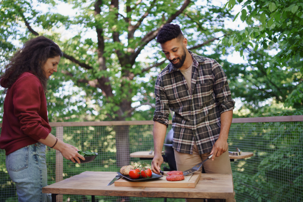 A happy couple resting and preparing burgers outdoors in a tree house, weekend away and digital detox concept.