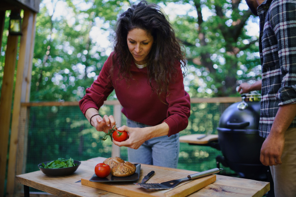 A happy biracial couple resting and preparing burgers outdoors in a tree house, weekend away and digital detox concept.