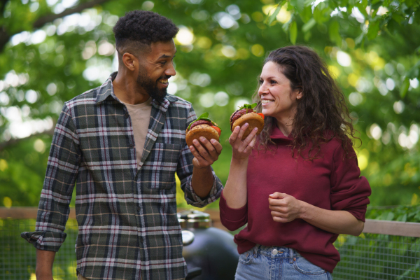 A happy couple resting and eating burgers outdoors in a tree house, weekend away and digital detox concept.