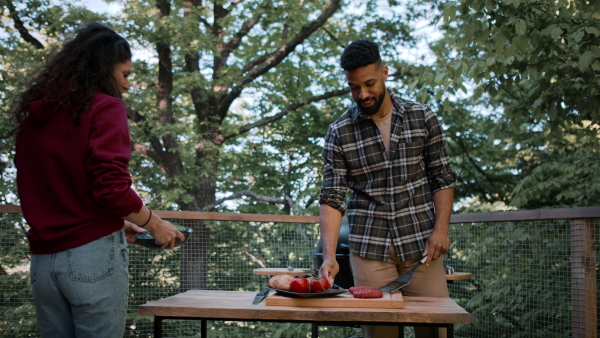 A happy couple resting and preparing burgers outdoors in a tree house, weekend away and digital detox concept.