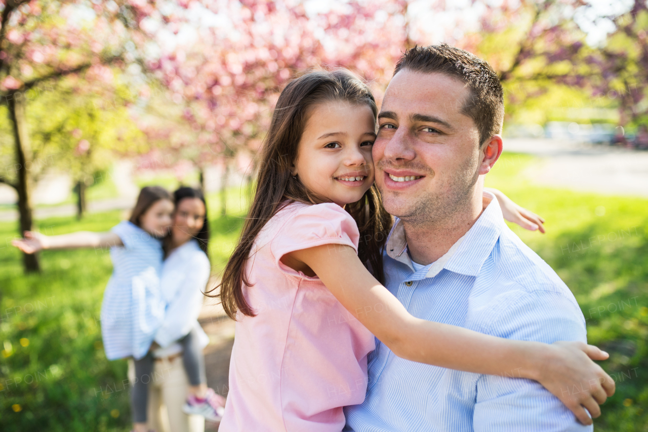 Family of young parents with small daughters standing outside in spring nature, having fun.