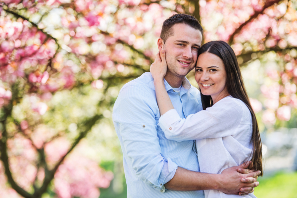 Young couple in love standing outside in spring nature. Copy space.