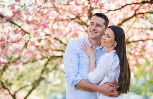 Young couple in love standing outside in spring nature. Copy space.