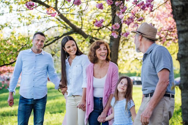 Three generation family on a walk outside in spring nature, holding hands.