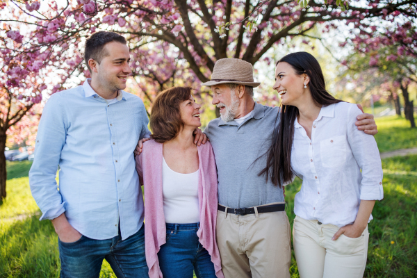 A young couple with senior parents walking outside in spring nature.