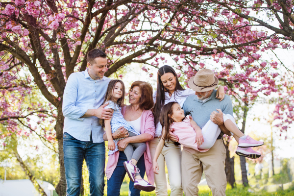 Front view of three generation family standing outside in spring nature, looking at camera.