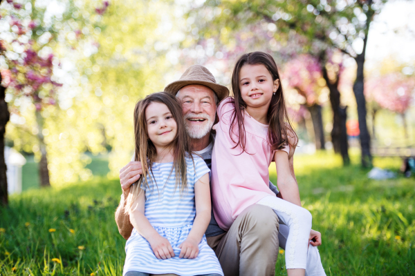 A senior grandfather with granddaugthers outside in spring nature.