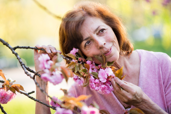 Front view of beautiful senior woman standing outside in spring nature. Copy space.