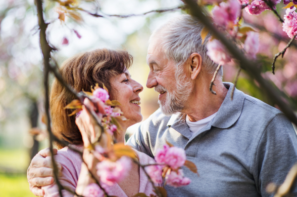 Front view of beautiful senior couple in love outside in spring nature, talking.