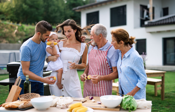 Front view portrait of multigeneration family outdoors on garden barbecue.