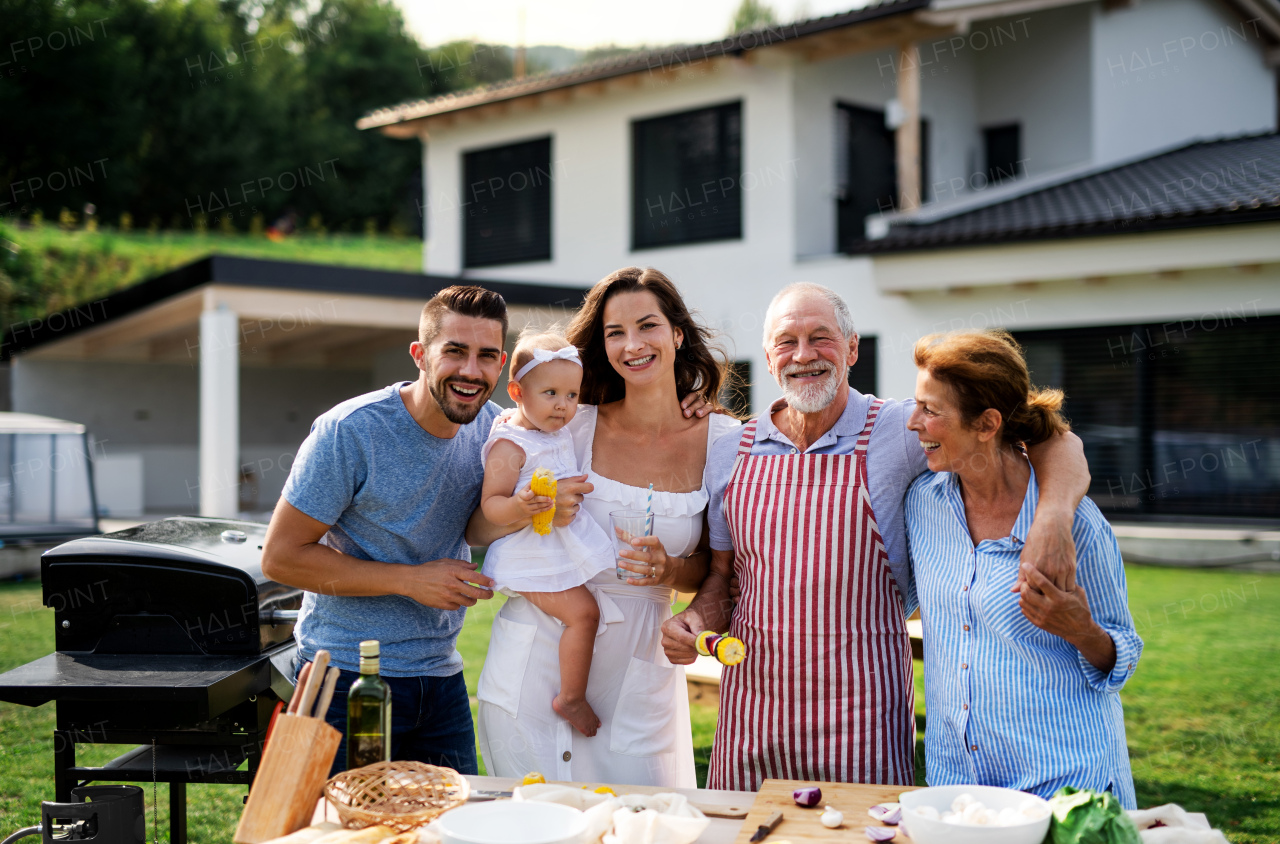 Front view portrait of multigeneration family outdoors on garden barbecue.