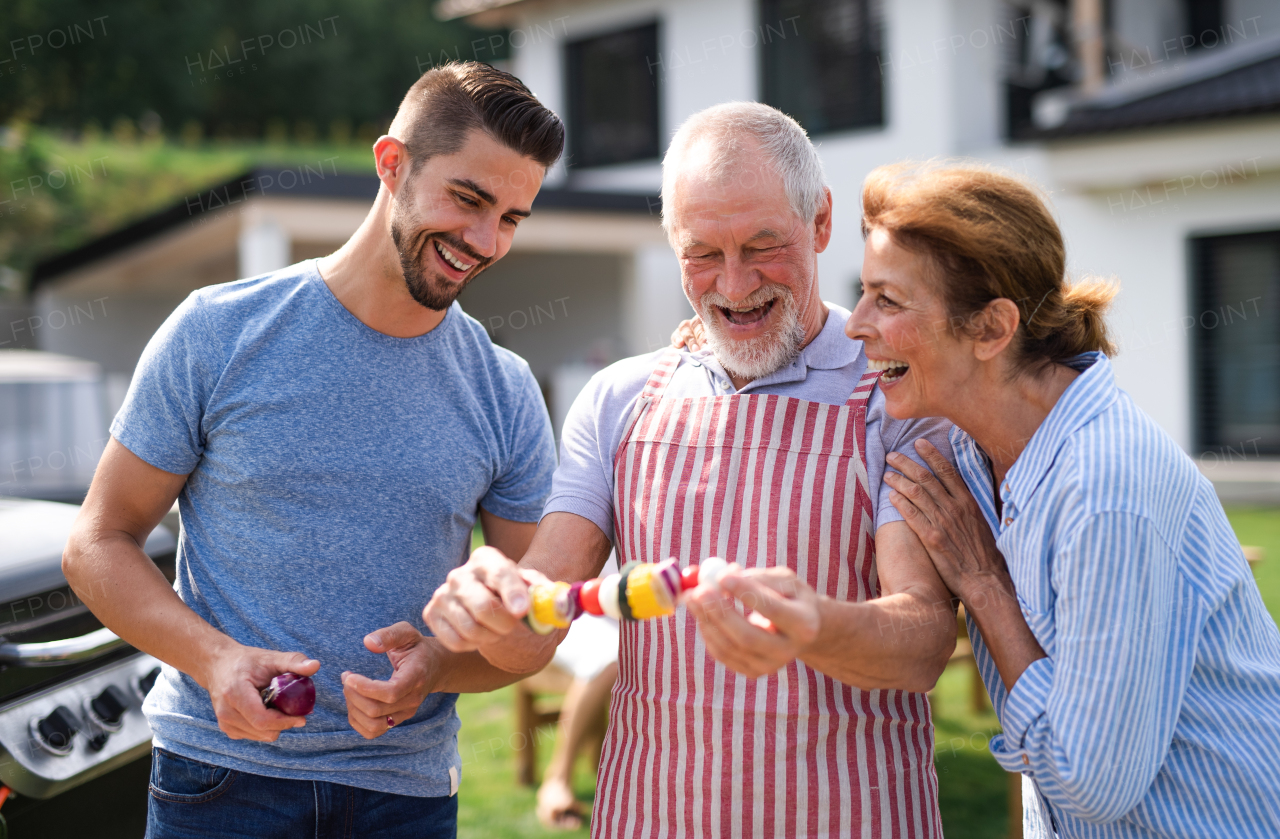 Portrait of multigeneration family outdoors on garden barbecue, grilling and talking.