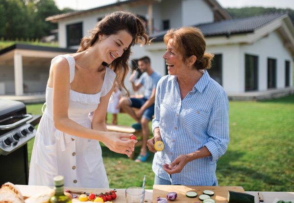 Portrait of multigeneration family outdoors on garden barbecue, grilling and talking.