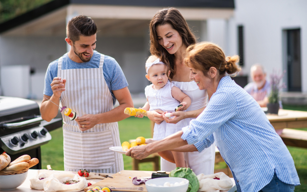 Portrait of multigeneration family outdoors on garden barbecue, grilling and talking.