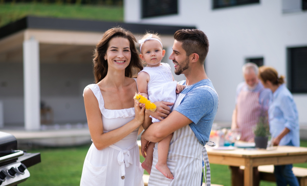 Portrait of happy family with baby outdoors on garden barbecue, grilling.