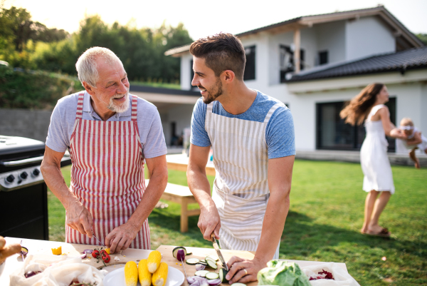 Portrait of father and son outdoors on garden barbecue, grilling and talking.