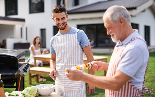 Portrait of multigeneration family outdoors on garden barbecue, grilling and talking.