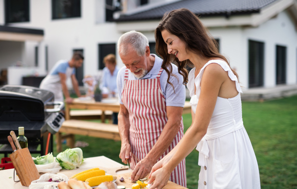 Portrait of multigeneration family outdoors on garden barbecue, grilling and talking.