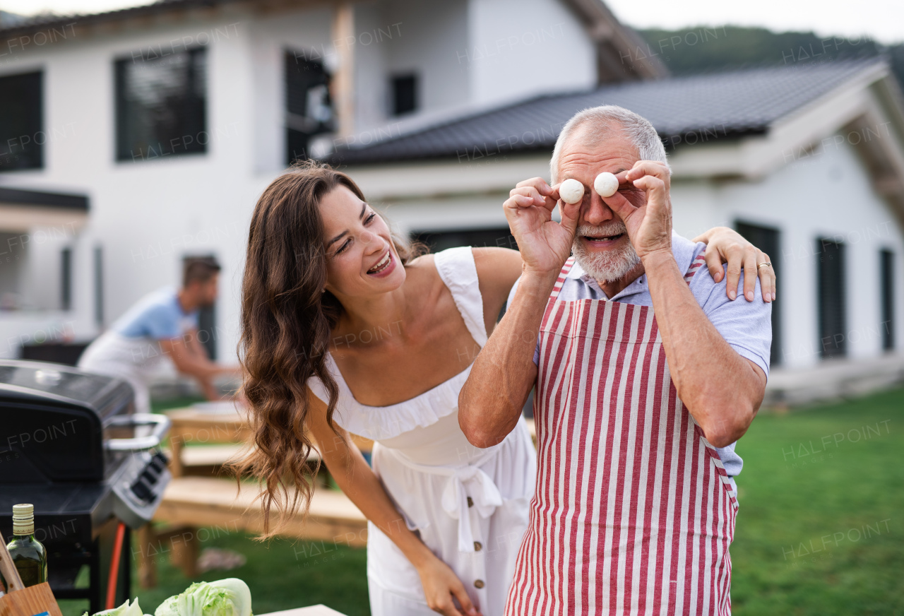 A multigeneration family outdoors on garden barbecue, having fun when grilling.