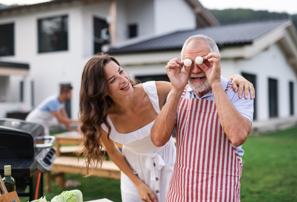 A multigeneration family outdoors on garden barbecue, having fun when grilling.