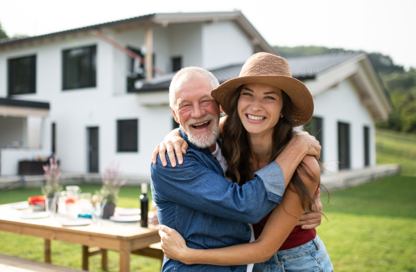 Portrait of senior father with daughter outdoors in backyard, looking at camera.