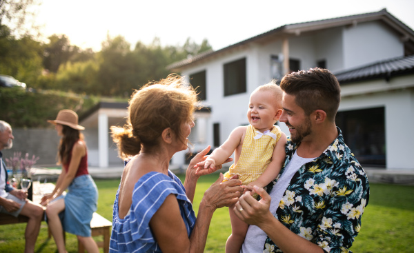 A portrait of multigeneration family outdoors on garden barbecue.