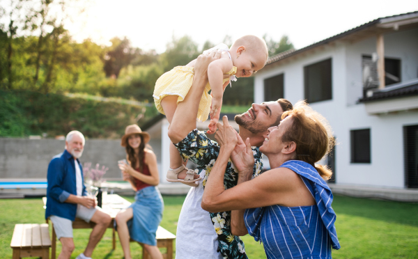 A portrait of multigeneration family outdoors on garden barbecue.