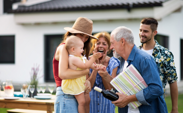 A portrait of multigeneration family outdoors on garden barbecue.